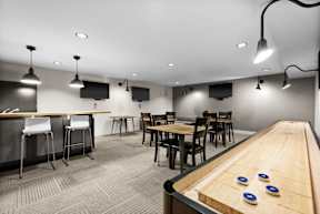 A room with a shuffleboard table and bar area.