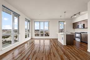 A spacious kitchen and living room with wooden floors and large windows.