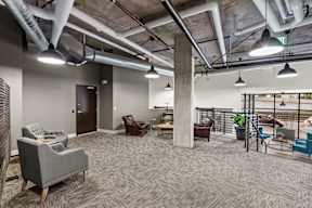 A spacious office with grey carpeting and a variety of seating options.