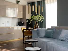 A modern living room with a sofa, a coffee table, and a kitchen area in the background.