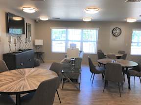 A room with a round table and chairs, a flat screen TV, and a large window.