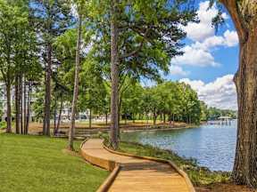 A wooden walkway runs along the edge of a lake, bordered by trees.