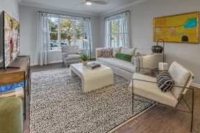 A living room with a white couch, a coffee table, and a painting on the wall.