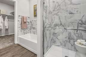 A bathroom with a marble tile wall and a white toilet.
