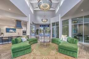 A living room with green couches and a large chandelier.