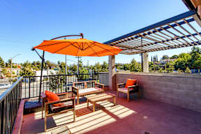 A patio with a table and chairs under an orange umbrella.