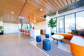 A modern living room with a wooden ceiling and a striped rug on the floor.