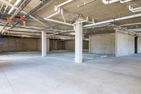 A large, empty industrial space with concrete floors and exposed pipes.