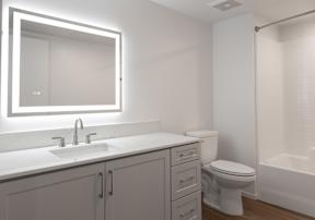 A white bathroom with a sink, toilet, and mirror.