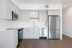 A kitchen with white cabinets and a stainless steel refrigerator.