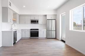 A modern kitchen with stainless steel appliances and wooden floors.