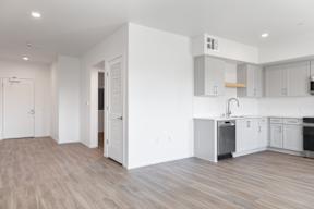 A kitchen with white cabinets and a wooden floor.