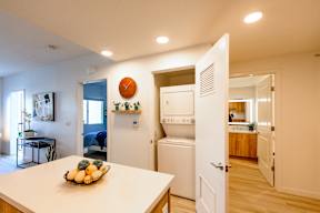 A kitchen with a white table and a bowl of fruit on it.