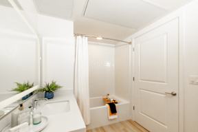 A white bathroom with a white sink, white bathtub, and white walls.