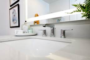 A white sink with a silver faucet and a mirror above it.