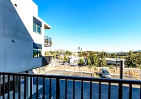 A balcony overlooks a parking lot and buildings.