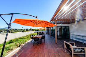 A patio with a table and chairs under an orange umbrella.