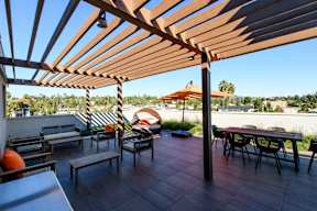 A patio with a table and chairs under a wooden pergola.