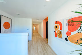 A hallway with artwork on the walls and a plant on the right.