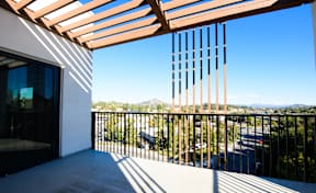 A balcony with a wooden pergola and a view of the street below.