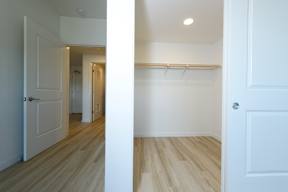 A white door is open to a hallway with a white wall and a white closet with a white door.