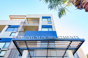 A tall building with the words "Rising Sun Apartments" on the front.