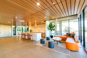 A modern living room with a wooden ceiling and a white kitchen in the background.