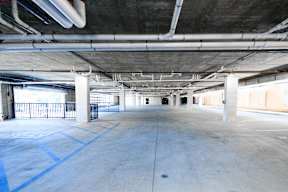 A large, empty parking garage with concrete floors and white pillars.
