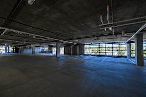 A large, empty warehouse with concrete floors and exposed ceiling beams.