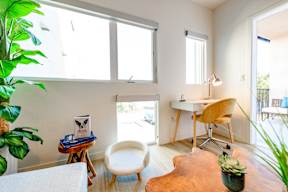 A room with a desk, chair, and potted plant.