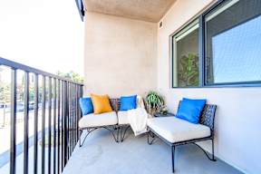 A patio with two white couches and blue pillows.