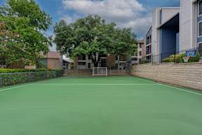 A tennis court surrounded by trees and buildings.