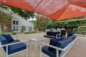 A patio with blue chairs and a red umbrella.