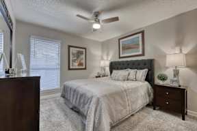 A bedroom with a bed, nightstand, and a painting on the wall.