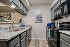A kitchen with granite countertops and a black stove top oven.