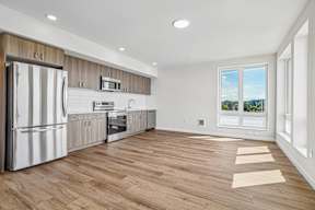 A modern kitchen with wooden cabinets and a stainless steel refrigerator.