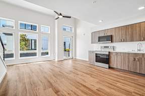A modern kitchen with wooden floors and stainless steel appliances.