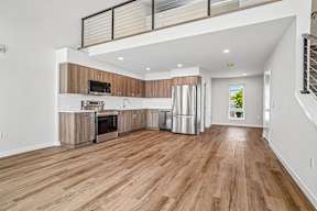 A spacious kitchen with wooden floors and white walls.