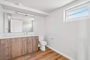 A bathroom with a toilet, sink, and mirror.