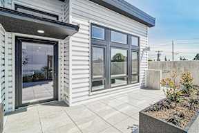 A modern house with a grey exterior and a glass door.