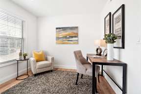 A living room with a chair, a table, and a painting on the wall.