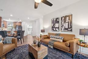 A living room with a brown couch and a ceiling fan.