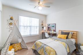A bedroom with a bed, a teepee, and a desk.