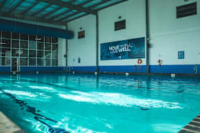 A swimming pool with the words "Move Well Live Well" on the wall.