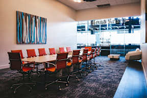 A conference room with red chairs and a large painting on the wall.