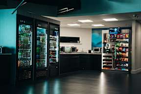 A modern bar with a black counter and a variety of drinks and snacks.