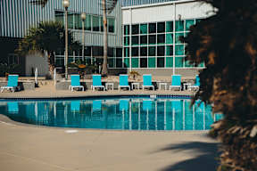 A pool with blue water and chairs around it.