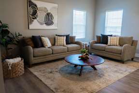 A living room with a large couch, a coffee table, and a painting on the wall.