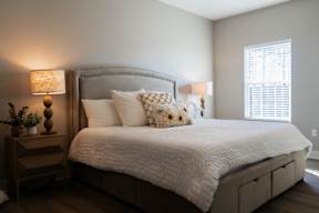 A bedroom with a large bed and a nightstand with a lamp.