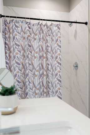 A shower curtain with a leaf pattern hangs over a bathroom sink.
